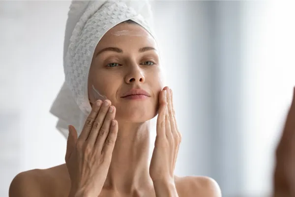 Młody mężczyzna z uśmiechem próbuje wyciskać wągry na nosie